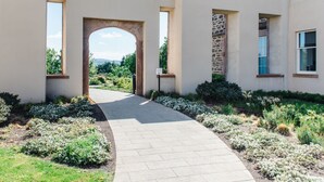 A pathway leading to an archway in a building with a stone facade and a view of greenery in the distance. - Great Glen View by Interhome (Inverness)