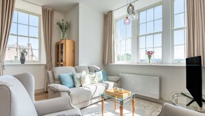 A modern living room with a sofa, armchairs, a glass coffee table, and a television. - Great Glen View by Interhome (Inverness)