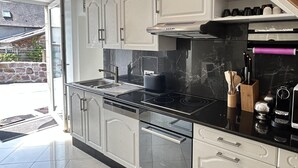 Una cocina moderna con armarios blancos, encimera negra y campana extractora de acero inoxidable.