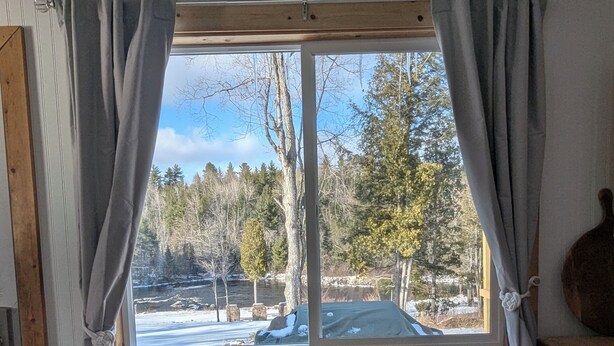 A room with a large window, wooden bench, and curtains.