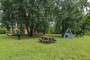 Ein Park mit Picknicktischen, einem Spielplatz und einer Kletterkonstruktion.