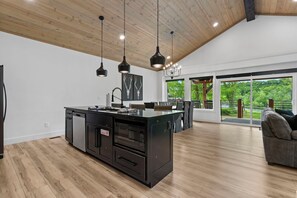 A spacious kitchen with a central island, pendant lighting, and a view of the outdoors.