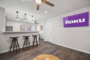 Een moderne keuken met een bar, houten krukken en een plafondventilator.