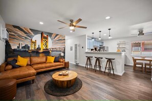 Een moderne woonkamer met een bank, bijzettafeltje en een stadsmuur als decoratie.