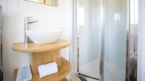 A bathroom with a white sink, a mirror, and a glass shower enclosure.