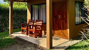Un espace extérieur abrité, doté de deux bancs en bois, d’une porte en bois et d’une fenêtre.