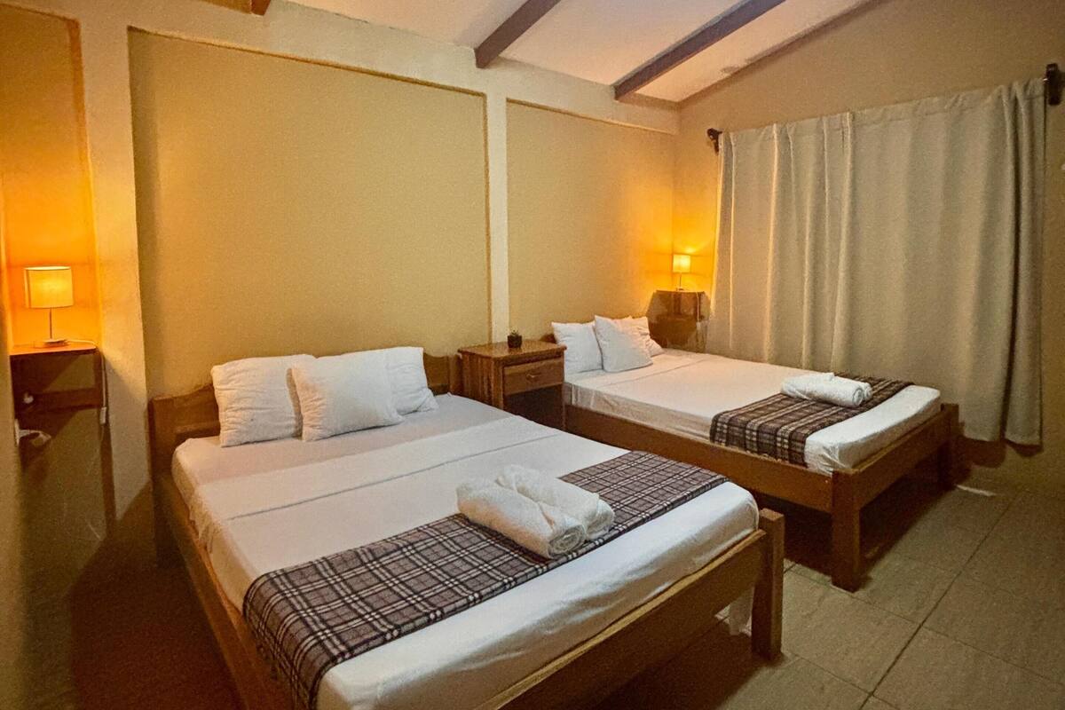 A hotel room with two beds, a ceiling fan, and a nightstand with a lamp.