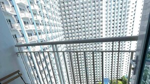 A balcony with a view of high-rise buildings, a small table, and a bench. - Jazz Residences Tower B +Wifi & Netflix (Makati)