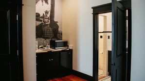 Un pasillo con una zona de cocina, un microondas y una puerta que da a otra habitación.