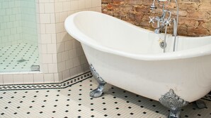 Un baño con pared de ladrillo, cabina de ducha de vidrio y bañera independiente.