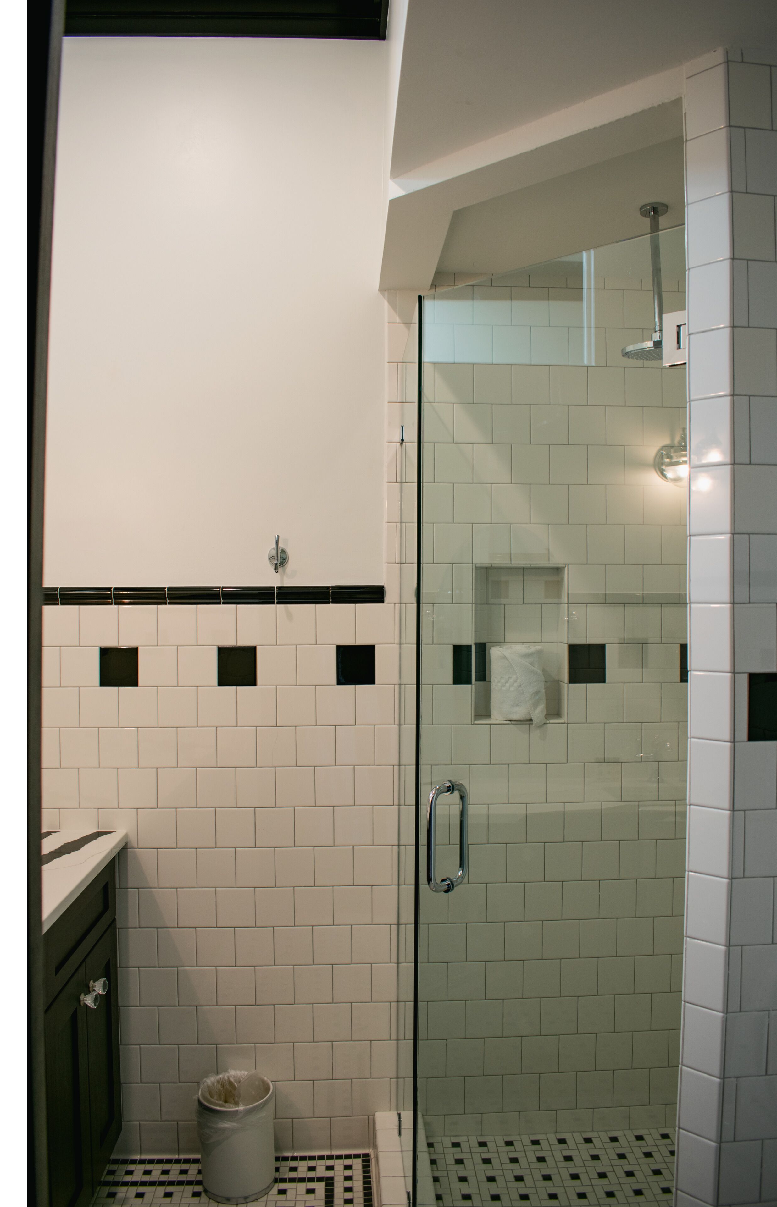 A glass-enclosed shower with white tiles and a small towel shelf.