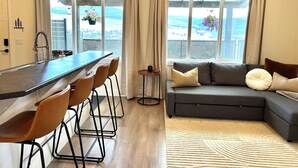 A modern kitchen with a bar area, a sofa, and a view of the outdoors.