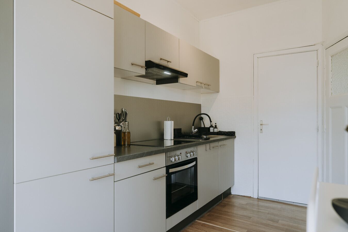 Een moderne keuken met witte kasten, een zwarte kookplaat en een roestvrijstalen spoelbak.