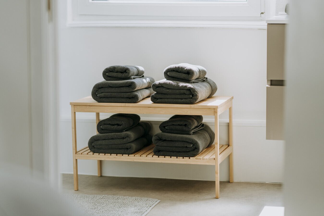 A wooden shelf with neatly folded dark-colored towels.