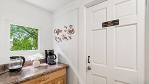 Una cocina con cafetera, hervidor y un cartel en la puerta.