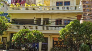 A multi-story hotel with balconies, a sign indicating it is a hotel, and a street in front with parked motorcycles. - LISEKA HOTEL (Phnom Penh)