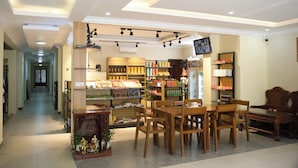 A well-lit store with wooden furniture, shelves stocked with various products, and a visible aisle leading to a door. - LISEKA HOTEL (Phnom Penh)
