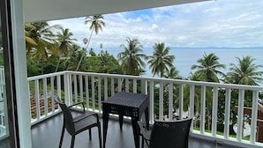 A balcony with a table and chairs, overlooking a beach with palm trees and the sea. - Apartamento Vista Mare 16-301 (Samaná)
