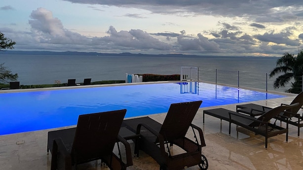 An infinity pool with lounge chairs, a view of the sea, and a cloudy sky. - Apartamento Vista Mare 16-301 (Samaná)