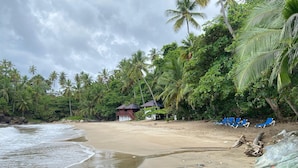A beach with palm trees, a small wooden structure, and blue lounge chairs. - Apartamento Vista Mare 16-301 (Samaná)
