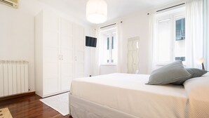 A bedroom with a bed, a radiator, a wardrobe, and a window with curtains.