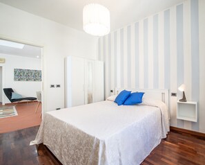 Une chambre à coucher avec un lit, une table de chevet, une chaise, une armoire et un tableau au mur.