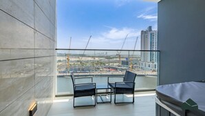 A modern balcony with a view of a construction site and high-rise buildings. - Canal View Studio | Private Jacuzzi | BMS (Dubai)