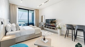 Et moderne hotelværelse med en stor seng, fjernsyn, skrivebord og balkon med udsigt over byen.