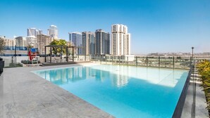 A rooftop swimming pool with a city skyline in the background. - Canal View Studio | Private Jacuzzi | BMS (Dubai)