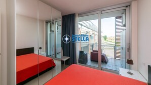 Une chambre d’hôtel comprenant un lit, une chaise, une table et une porte-fenêtre coulissante donnant sur un espace extérieur.