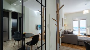 A modern living room with a sofa, a dining table with chairs, and a glass partition.