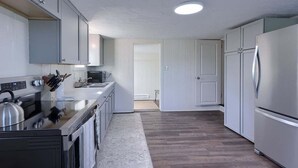 Een moderne keuken met witte kastjes, roestvrijstalen apparatuur en een houten vloer.