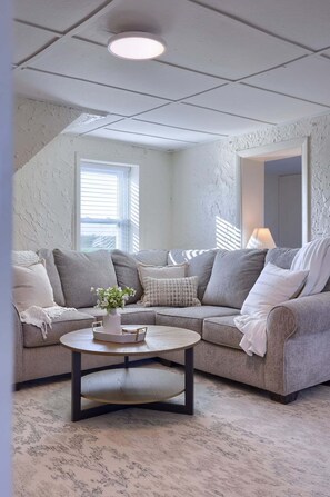 A living room with a sectional sofa, a round coffee table, and a ceiling light.