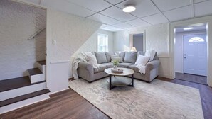 Een woonkamer met een hoekbank, een salontafel en een trap.