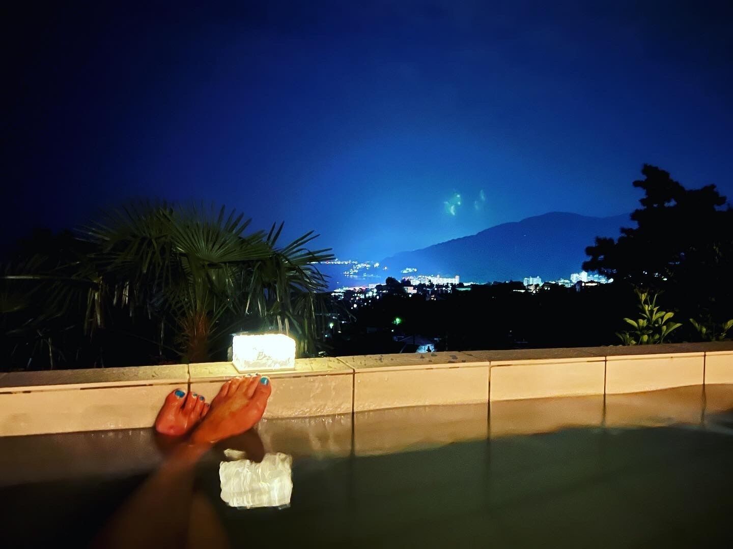 A night view from a balcony with a cityscape and a mountain in the background.