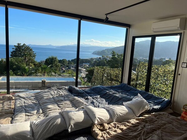 Une chambre dotée d’un grand lit, offrant une vue sur la mer et les montagnes, et équipée d’un climatiseur.
