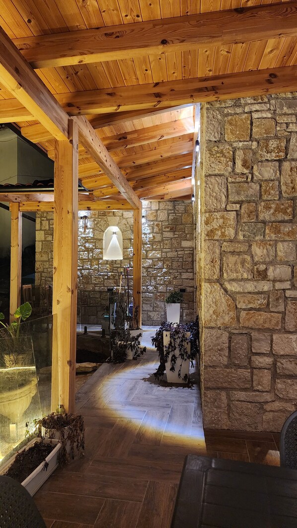 Un intérieur aux murs de pierre, avec des poutres en bois, une cheminée en pierre et des plantes en pot.