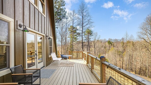 A wooden deck with outdoor seating and a scenic view of trees. - Modern A-Frame Away from it All! (Marshall)