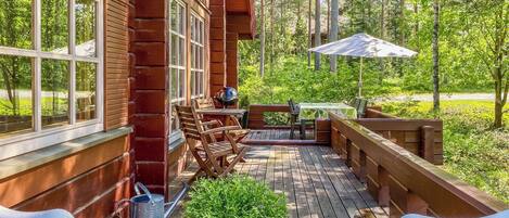 A wooden deck with outdoor furniture, a grill, and a potted plant.