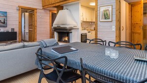 Una sala de estar acogedora con chimenea, un comedor con mesa y sillas, y una cocina al fondo.