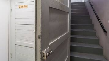 A closed door with a sign that reads 'suna' and a staircase with a handrail.