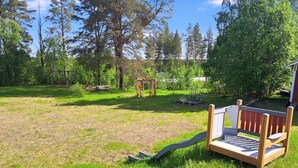 A backyard with a wooden play structure, a picnic table, and a garden area.