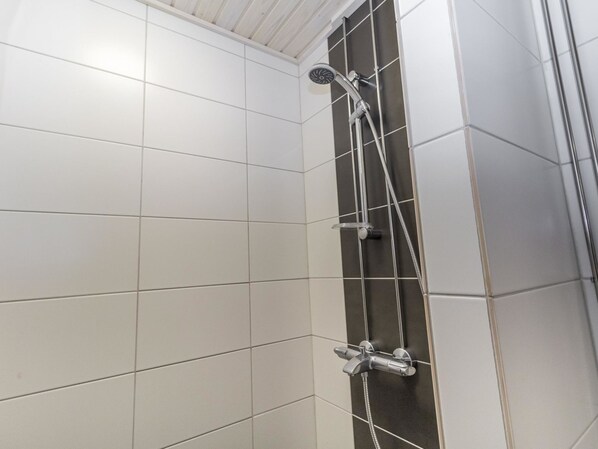 A shower area with white tiles and a black-tiled wall.