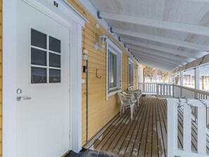 A wooden porch with a white door and windows, outdoor seating, and a railing. - Kelloselkä b by Interhome (Salla)