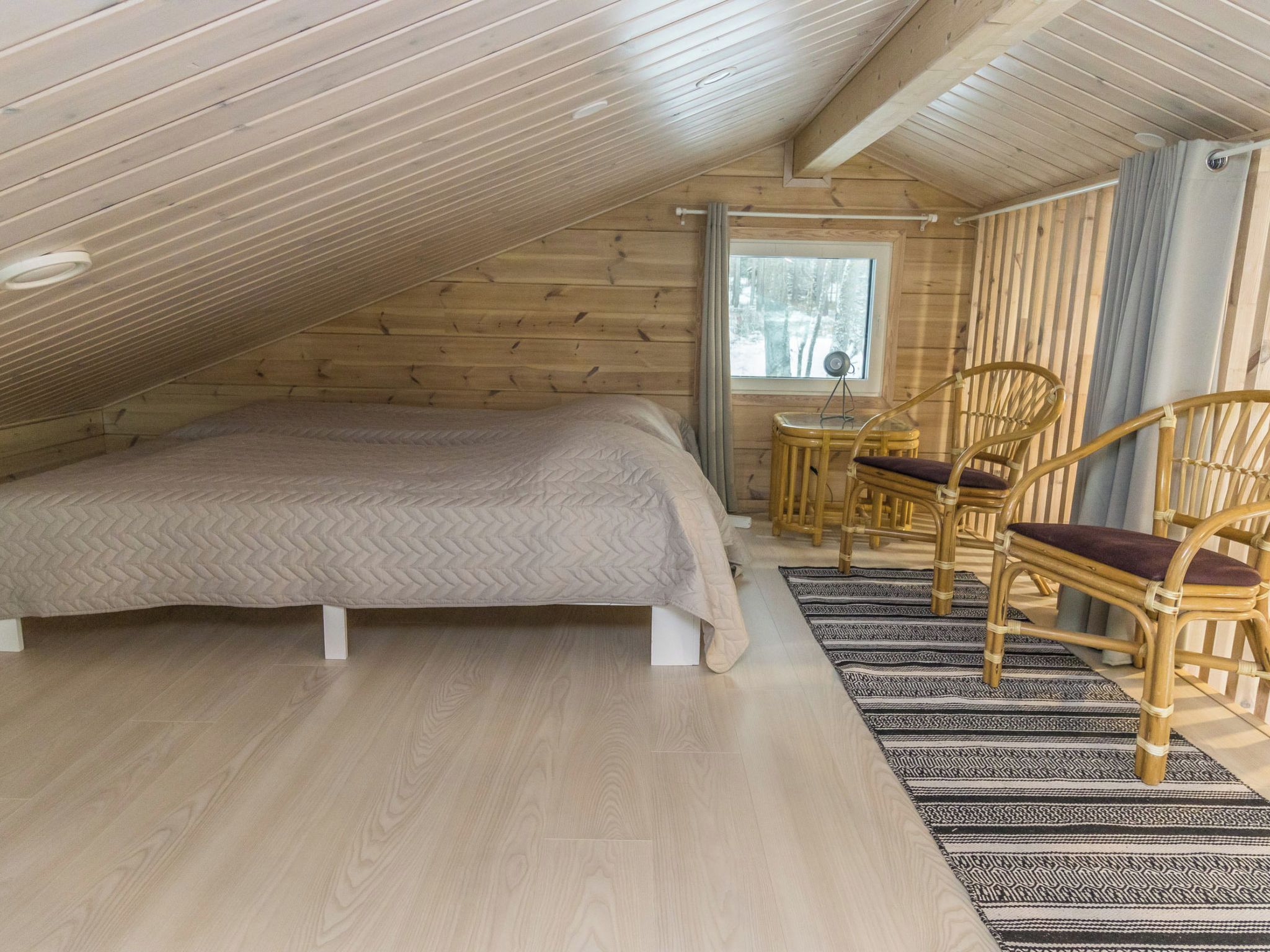 Een slaapkamer met een bed, twee stoelen, een klein tafeltje en een raam.