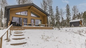 A wooden cabin with a large deck and a staircase leading up to it.