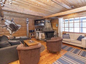 A log cabin interior with a stone fireplace, wooden furniture, and a mounted television. - Savottakämppä by Interhome (Sodankylä)