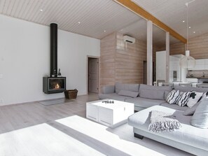 A modern living room with a fireplace, a sofa, a coffee table, and a kitchen area.
