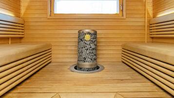 A sauna room with wooden benches, a central stone pillar, and a window.
