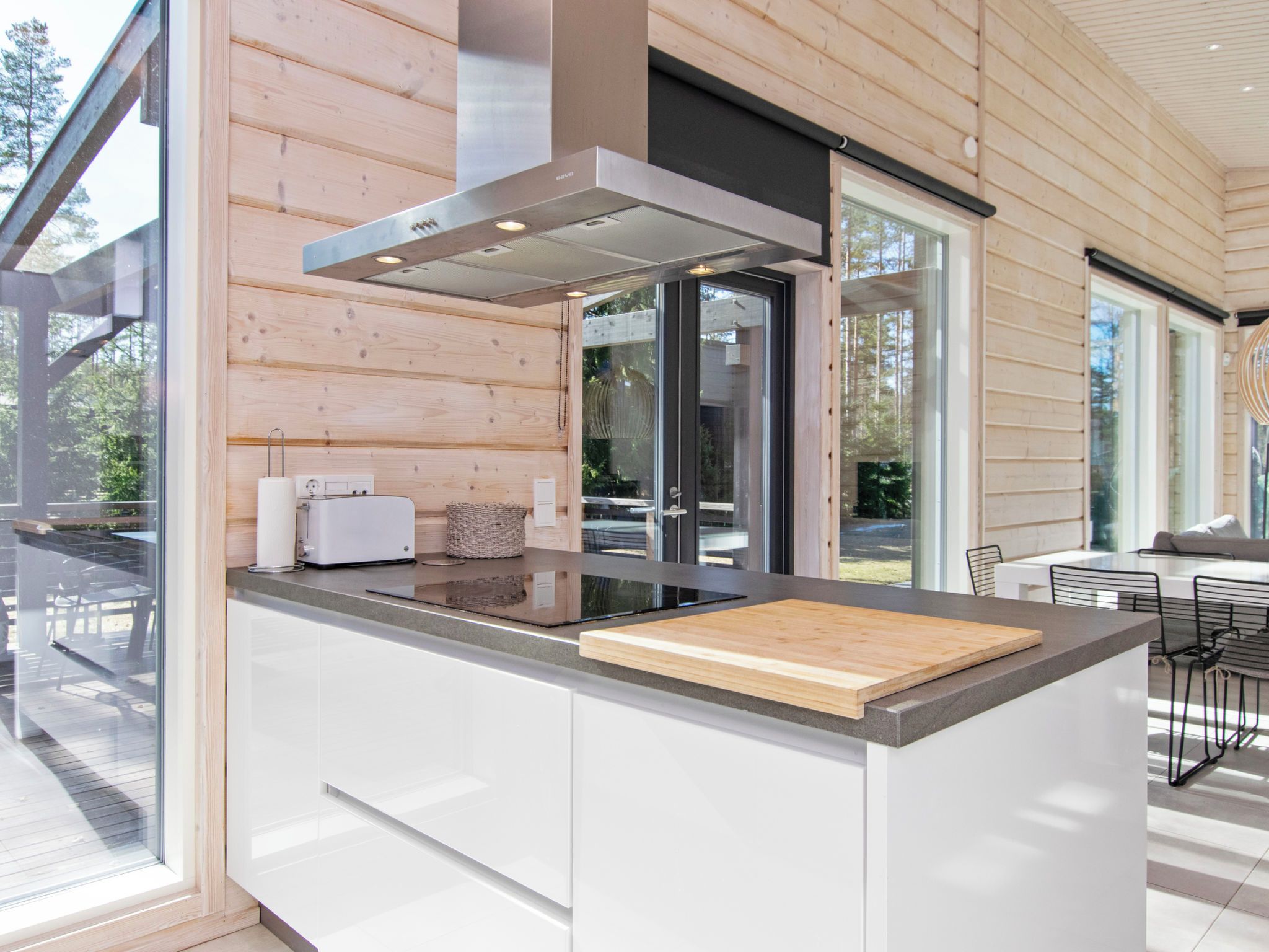 Una cocina moderna con una isla grande, paneles de madera y vistas al exterior.